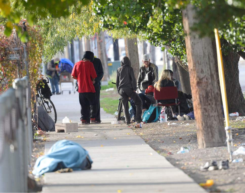 Al Hartmann  |  The Salt Lake Tribune
Homeless gather for the day in one of many small camps in the Rio Grande neighborhood.  This one on the sidewalk along 600 West and 150 South Friday morning October 28.  A man sleeps in blanket in the foreground.  Salt Lake City officials are planning for additional emergency shelter space for homeless people when temperatures begin to drop for the winter.