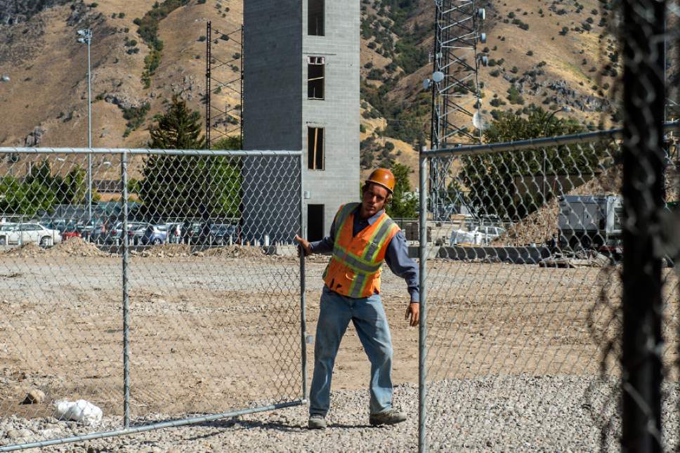 Chris Detrick  |  The Salt Lake Tribune
An employee with Phaze Concrete closes the gate at the construction site of a new residence hall at Utah State University Thursday September 1, 2016.