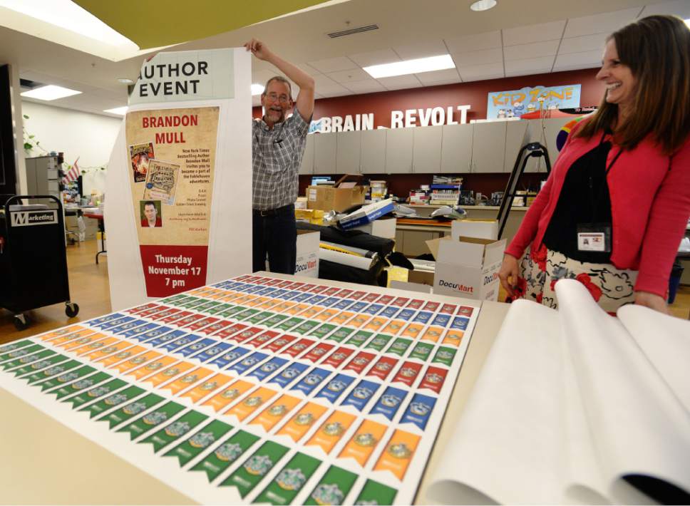 Steve Griffin / The Salt Lake Tribune

Marketing and communications specialist Tracy Hampton holds up a poster he created in-house at the Salt Lake County Library System's Viridian Library in West Jordan on Thursday, Oct. 27, 2016. Marketing and Community Relations Manager Liz Sollis, right, says many of the library system's marketing and advertising graphic needs are met at the offices in the Viridian Library. The Salt Lake County Library System is being honored once again for being a good place to work.