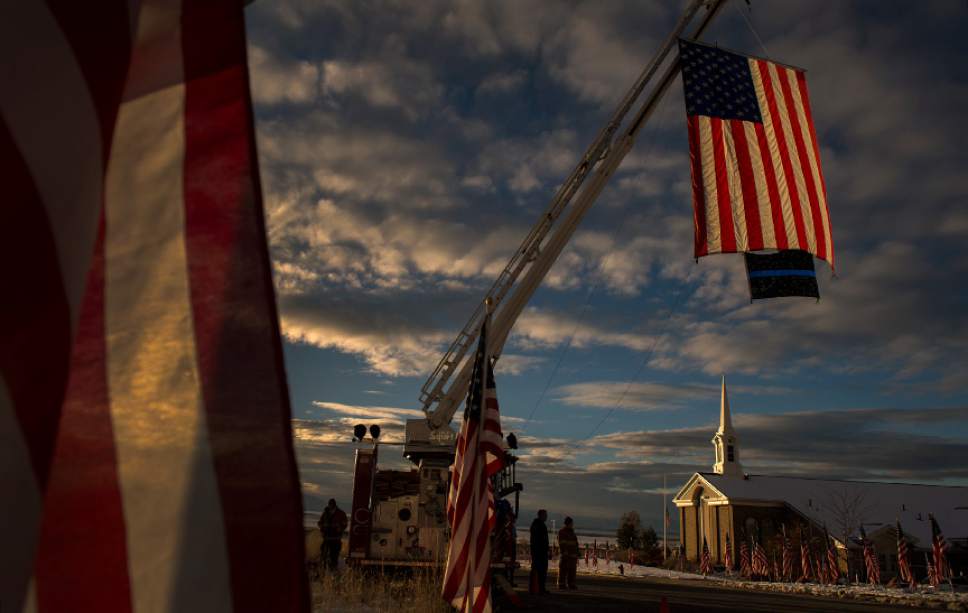 Leah Hogsten  |  The Salt Lake Tribune
Flags flown from the ladder truck of the Willard Fire Department blow in the breeze at the entrance to the Willard LDS Stake Center, as friends, loved ones and police officers from Utah and several U.S. state agencies arrive to pay their respects to the family of Utah Highway Patrol Trooper Eric Ellsworth, who was hit by a car earlier this month†while trying to alert the driver of a semitrailer truck to go around a downed power line in Box Elder County. Ellsworth died four days later.
