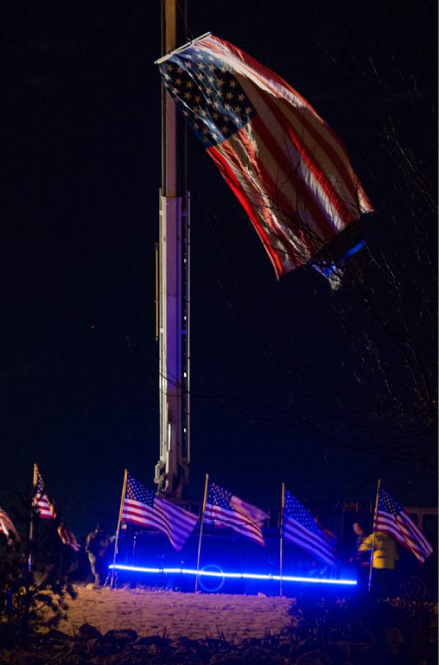 Leah Hogsten  |  The Salt Lake Tribune
Lighted flags flown from the ladder truck of the Willard Fire Department blow in the breeze at the entrance to the Willard LDS Stake Center, as friends, loved ones and police officers from Utah and several U.S. state agencies arrive to pay their respects to the family of Utah Highway Patrol Trooper Eric Ellsworth, who was hit by a car on the night of November 18, 2016 while trying to alert the driver of a semitrailer truck to go around a downed power line in Box Elder County. Ellsworth died four days later.