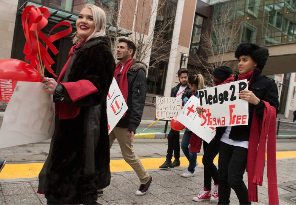 Leah Hogsten  |  The Salt Lake Tribune
l-r In honor of World AIDs Day, anti-AIDS activists, Caitlin Caouette, Frank Castro and Danny Pitcher handed out red scarves to passersby along Main Street to raise awareness about the stigma of AIDS.  Read My Lips: Kiss In and Stick it to Stigma Rally started at City Creek TRAX station and ended at the Salt Lake City and County Building.