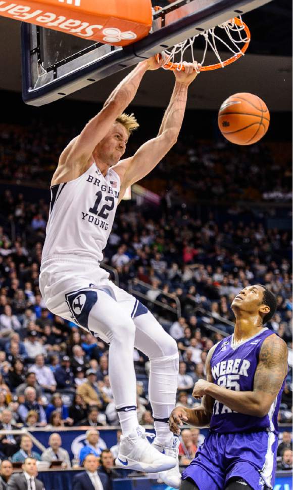 Trent Nelson  |  The Salt Lake Tribune
Brigham Young Cougars forward Eric Mika (12) dunks over Weber State Wildcats forward Kyndahl Hill (35) as BYU hosts Weber State, NCAA basketball at the Marriott Center in Provo, Wednesday December 7, 2016.
