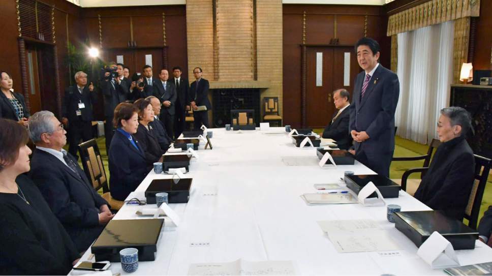 Japanese Prime Minister Shinzo Abe, second right, speaks to a group of former residents of the Russian-held islands off Japan's major northern island of Hokkaido during a meeting at the prime minister's official residence in Tokyo Monday, Dec. 12, 2016. The meeting was held three days before Abe's meeting with Putin in Japan later in the week. A dispute over the southern Kuril islands, which Japan calls the Northern Territories, has kept the two countries from signing a peace treaty formally ending their World War II hostilities. The Soviet Union seized them in the war's final days. (Kyodo News via AP)