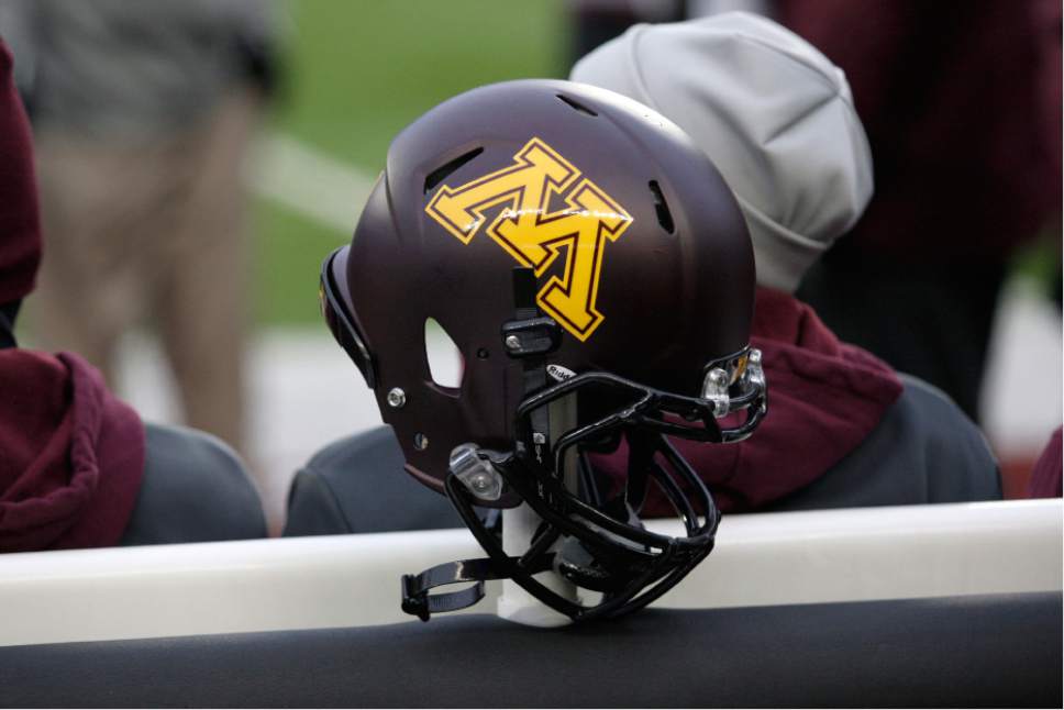 FILE - In this Nov. 24, 2012, file photo, a Minnesota helmet hangs on a sideline heater during an NCAA college football game against Michigan State, in Minneapolis. Ten Minnesota football players were suspended this week following a fresh investigation into an alleged sexual assault at an off-campus apartment in September, the father of a player and an attorney for several players said Wednesday, Dec. 14, 2016.(AP Photo/Paul Battaglia, File)