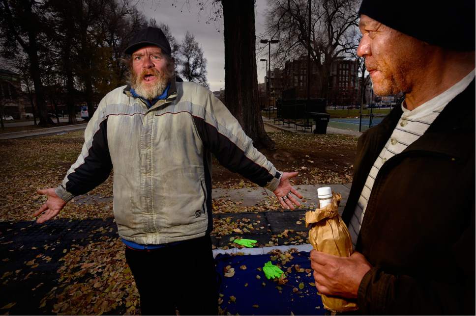 Scott Sommerdorf   |  The Salt Lake Tribune  
Mike Hubertz, left, describes an encounter he has with the police as he and his friend Saul Arrington share a cigarette and a bottle in Pioneer Park, Thursday, December 15, 2016.