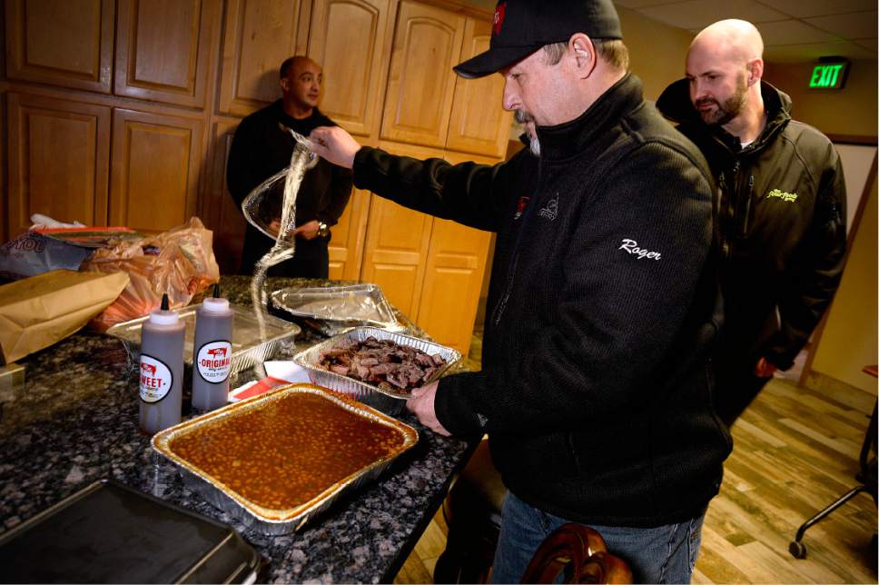 Scott Sommerdorf   |  The Salt Lake Tribune  
Roger Livingston, owner of R&R BBQ, unpacks a tray of baked beans to go along with bbq chicken, bbq beef, and cole slaw that he and Tyler Nelson, right, of Four Foods Group delivered to the Unified Fire Station in Draper, Saturday, December 24, 2016. Firefighter / paramedic Brad Jewett of Medic Ladder 105, waits in the background.