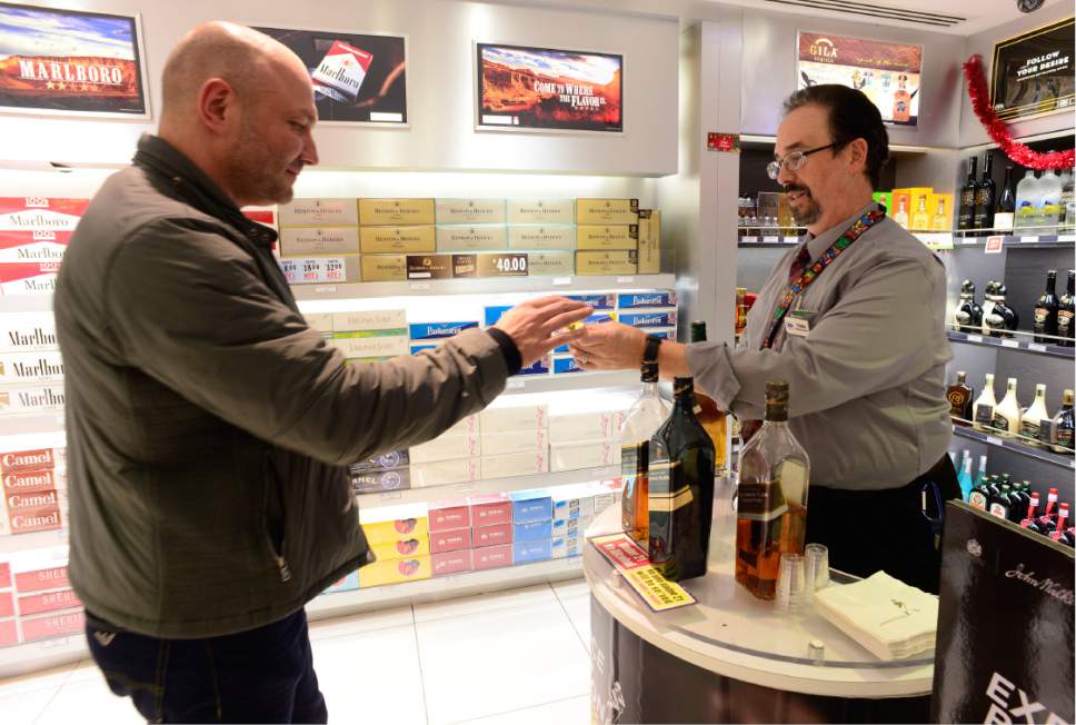 Scott Sommerdorf   |  The Salt Lake Tribune  
Simon Robson, who is about to fly to Amsterdam, takes a sample from assistant store manager Thomas Casey, right, from the samples bar. There are also minibottles of alcohol for sale at the Duty Free Americas shop at the Salt Lake City International Airport, Concourse D on Thursday.