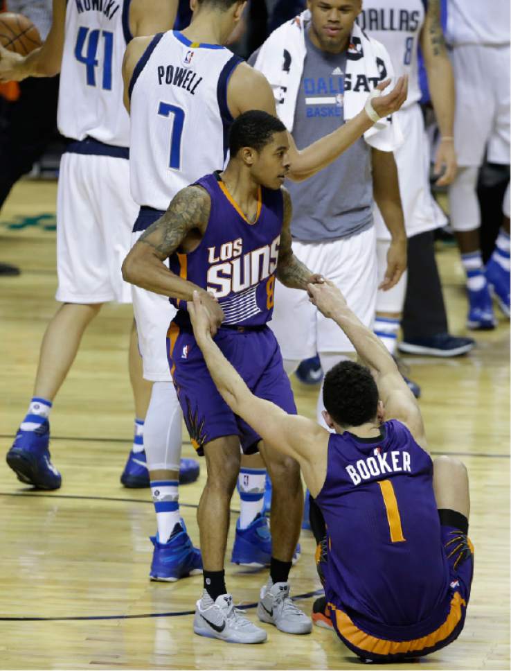 Phoenix Suns Tyler Ulis helps up teammate Devin Booker after losing to the Dallas Mavericks in a regular-season NBA basketball game in Mexico City, Thursday, Jan. 12, 2017. (AP Photo/Rebecca Blackwell)