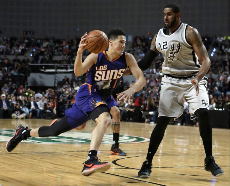 Phoenix Suns Devin Booker, left, drives the ball as San Antonio Spurs LaMarcus Aldridge attempts to block him, in the first half of their regular-season NBA basketball game in Mexico City, Saturday, Jan. 14, 2017. (AP Photo/Rebecca Blackwell)