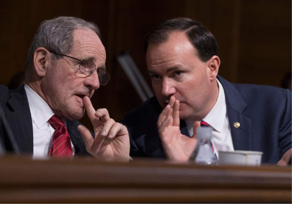 Senate Energy and Natural Resources Committee members Sen. Jim Risch, R-Idaho, left, and Sen. Mike Lee, R-Utah, confer on Capitol Hill in Washington, Tuesday Jan. 17, 2017, during the committee's confirmation hearing for Interior Secretary-designate Ryan Zinke. Zinke, 55, a former Navy SEAL who just won his second term in Congress, was an early supporter of President-elect Donald Trump and, like his prospective boss, has expressed skepticism about the urgency of climate change. (AP Photo/J. Scott Applewhite)