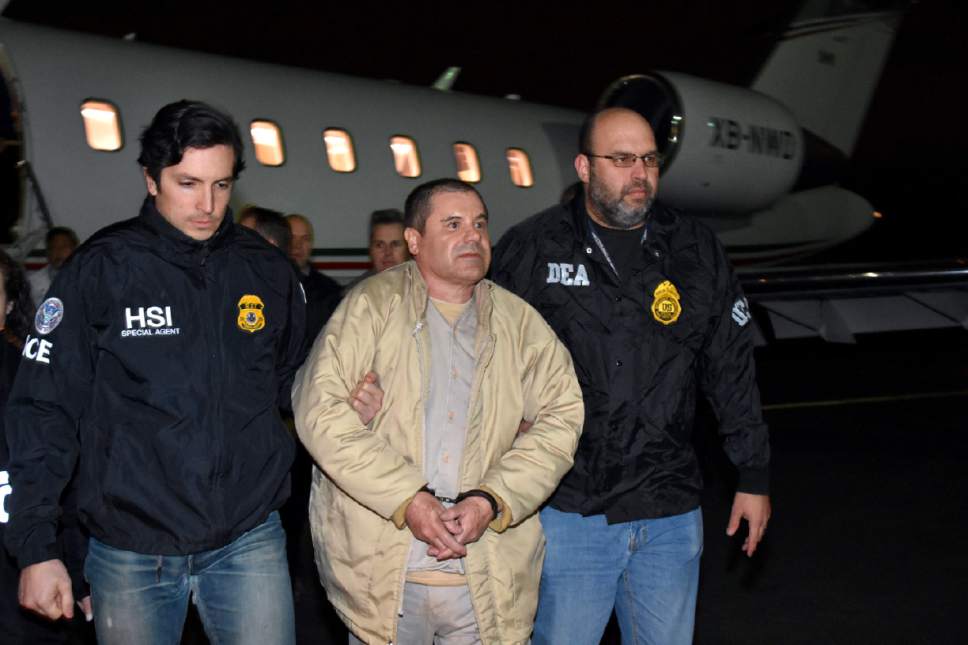 In this photo provided U.S. law enforcement, authorities escort Joaquin "El Chapo" Guzman, center, from a plane to a waiting caravan of SUVs at Long Island MacArthur Airport on Thursday, Jan. 19, 2017, in Ronkonkoma, N.Y. The infamous drug kingpin who twice escaped from maximum-security prisons in Mexico was extradited at the request of the U.S. to face drug trafficking and other charges, and landed in New York late Thursday, a federal law enforcement official said. (U.S. law enforcement via AP)