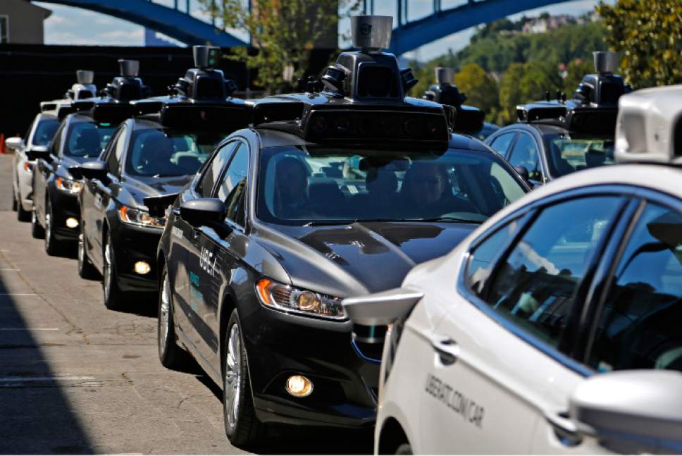 FILE - In this Monday, Sept. 12, 2016, file photo, a group of self-driving Uber vehicles position themselves to take journalists on rides during a media preview at Uber's Advanced Technologies Center in Pittsburgh. U.S. President Donald Trump's economic plans are nothing if not ambitious, including his vision of creating 25 million jobs over 10 years. However, the widespread use of robots and automation by companies has increasingly allowed businesses to operate with fewer workers. For example, Uber is experimenting with self-driving cars, and restaurant chains like Eatsa can now serve lunch and dinner through an automated order-and-payment system, and no cashiers or servers are necessary. (AP Photo/Gene J. Puskar, File)