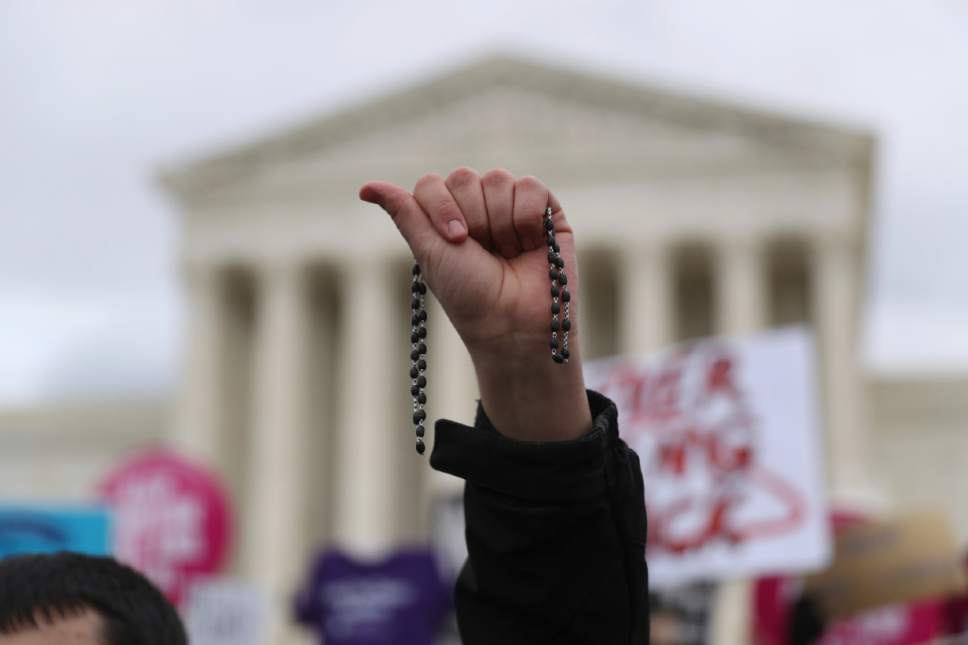 A participant in the annual March for Life holds up a rosary outside the Supreme Court in Washington, Friday, jan. 27, 2017. (AP Photo/Andrew Harnik)