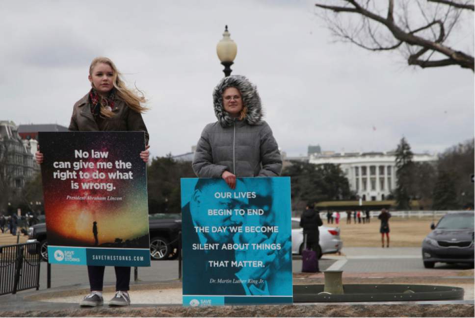Sarah Grim of Fayetteville, N.C., left, and Bethany Bostron of Williamsburg, Va., watch participants in the March for Life march near the White House, back right, in Washington, Friday, Jan. 27, 2017. (AP Photo/Manuel Balce Ceneta)