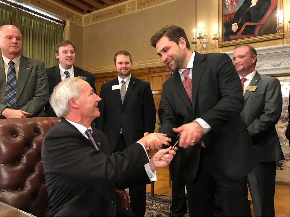 Arkansas Gov. Asa Hutchinson, left, shakes hands with Senate President Jonathan Dismang on Wednesday, Feb. 1, 2017, after signing legislation outlining a $50 million tax cut for thousands of low-income residents. A Senate panel endorsed a separate proposal aimed at forcing Amazon to collect state sales taxes, and lawmakers are eyeing the potential revenue from the move to help pay for future income tax cuts. (AP Photo by Andrew DeMillio)