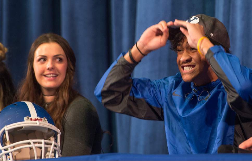 Leah Hogsten  |  The Salt Lake Tribune
l-r Bingham High School senior Megan Gurr, who will attend Utah State University to play volleyball watches Tongi Langi who slips on a BYU hat, indicating where he will play football in the fall.  Over 12 Bingham High School students announced their choices Wednesday, February 1, 2017 during the school's college signing day ceremony.
