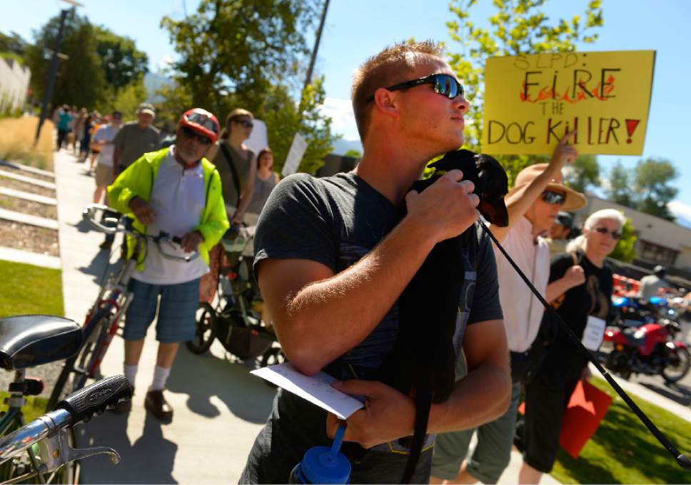 Leah Hogsten  |  Tribune file photo
Sean Kendall pets the dauschound of a fellow supporter at a protest rally in June as the sign holding marchers pass by. Hundreds of supporters of  Kendall and his dog, Geist, who was shot and killed in his backyard by a Salt Lake City police officer during a search for a missing child, rallied at the SLC Police headquarters to protest the officer's action.