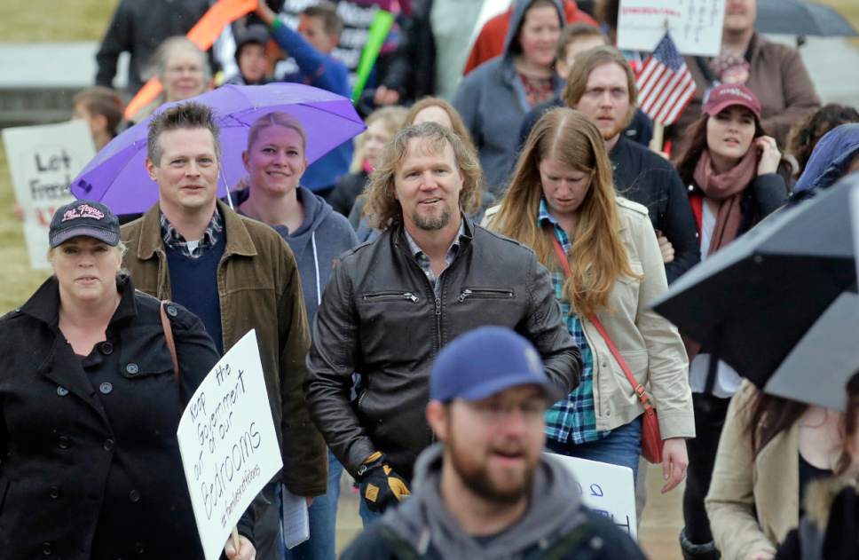 Salt Lake Tribune reporter Nate Carlisle, left, interviews Kody Brown, center, from TV's reality show "Sister Wives," as Brown marches during a protest at the state Capitol Friday, Feb. 10, 2017, in Salt Lake City. Several hundred people in polygamist relationships say they want Utah lawmakers and law enforcement officials to know that they're not going away and should be allowed the freedom to practice their plural marriages.  (AP Photo/Rick Bowmer)