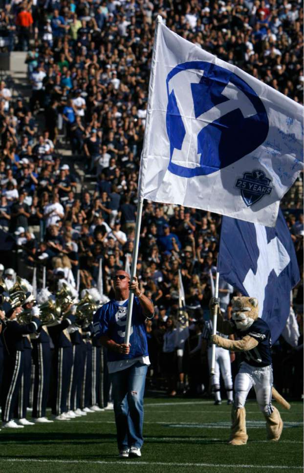 Trent Nelson  |  The Salt Lake Tribune

Former BYU quarterback Jim McMahon carries out the BYU flag pre-game with mascot Cosmo. BYU vs. Washington, at Lavell Edwards Stadium in Provo, Saturday, September 4, 2010.