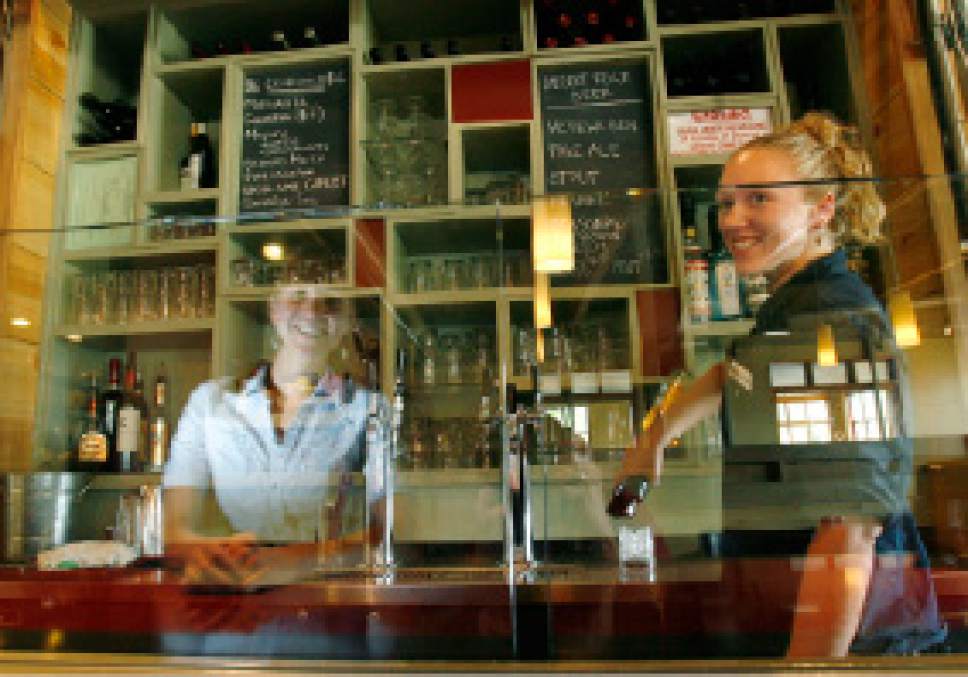 Salt Lake City- Stella Grill bartender Taylor Pape (right) makes a drink as manager Erin O'Conner sits at the counter and is reflected in what the restaurant calls the "Zion Curtain" which is a glass divider that separates the counter area from the bar area of the restaurant  Wednesday July 2, 2008.  Steve Griffin/The Salt Lake Tribune 7/2/08