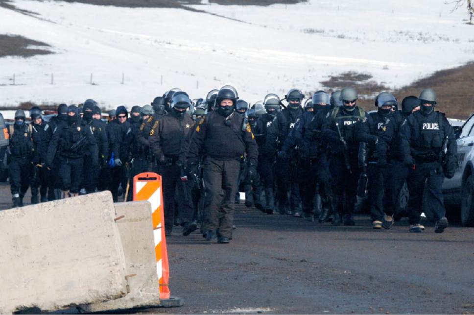 Several dozen law enforcement personal march south on Highway 1806 before assembling above the Oceti Sakowin camp to begin the final sweep of Dakota Access oil pipeline of the camp and arrests of protesters Thursday, Feb. 23, 2017, near Cannon Ball, N.D.  (Mike McCleary/The Bismarck Tribune via AP, Pool)
