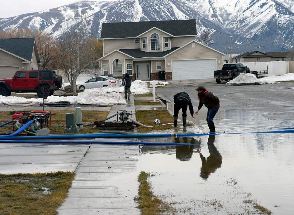 Al Hartmann  |  The Salt Lake Tribune
Amanda Mikesell, left, and her mother Vicki Summers man the pumps near 125 North 1650 West in Tremonton to pump standing water away from homes into the street Monday Feb. 20 before the next storm drops more rain.  Wellsville Mountains in the distance still hold much of the winter's snow. Parts of Box Elder County have seen surface flooding from the rapid snow melt and rain over the weekend.  Luckily these homes do not have basements but water rose nearly to the front doors of some homes.  Main Street in Tremonton from 1000 to 2000 West was closed last night to pump out the area.