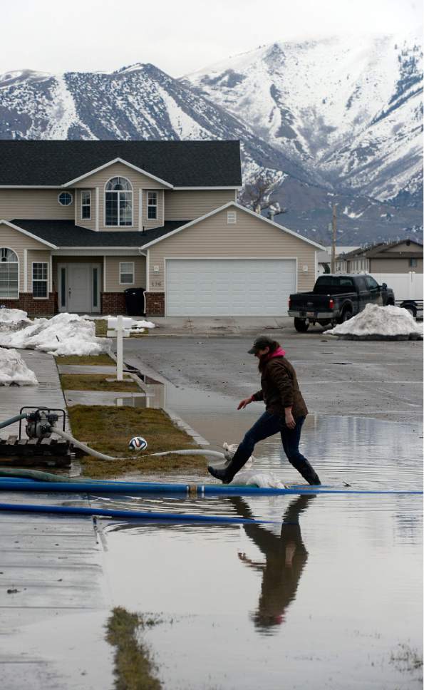 Al Hartmann  |  The Salt Lake Tribune
Vicki Summers mans the pumps near 125 North 1650 West in Tremonton to pump standing water away from her daughter's home and into the street Monday Feb. 20 before the next storm drops more rain.  Wellsville Mountains in the distance still hold much of the winter's snow. Parts of Box Elder County have seen surface flooding from the rapid snow melt and rain over the weekend.  Luckily these homes do not have basements but water rose nearly to the front doors of some homes.  Main Street in Tremonton from 1000 to 2000 West was closed last night to pump out the area.