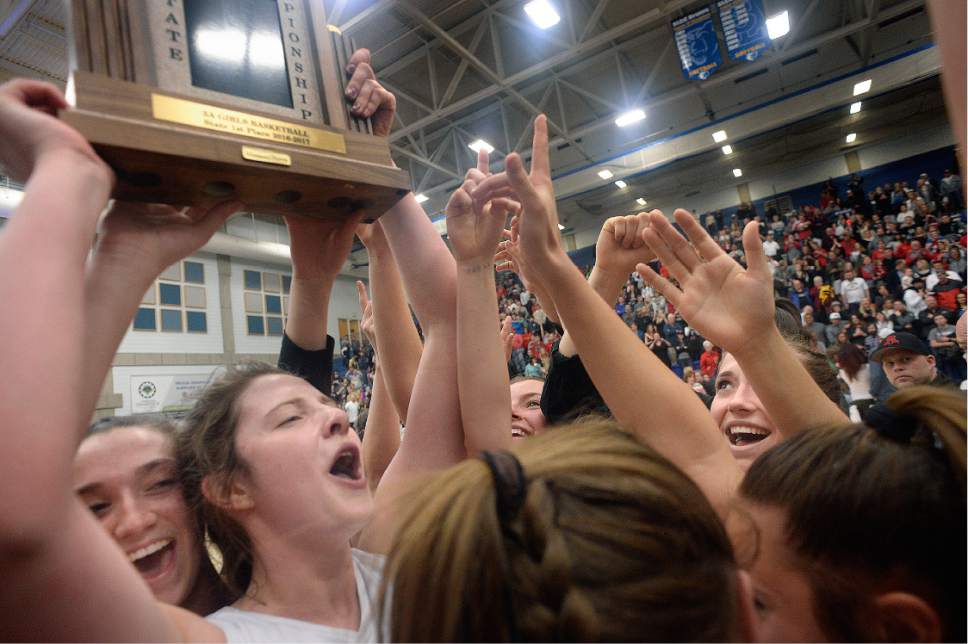 Scott Sommerdorf | The Salt Lake Tribune 
Taylor Franson holds the 5A Girls trophy as the American Fork players celebrate after winning the championship. American Fork defeated Viewmont 50-46 for the Girl's 5A championship, Saturday, February 25, 2017.