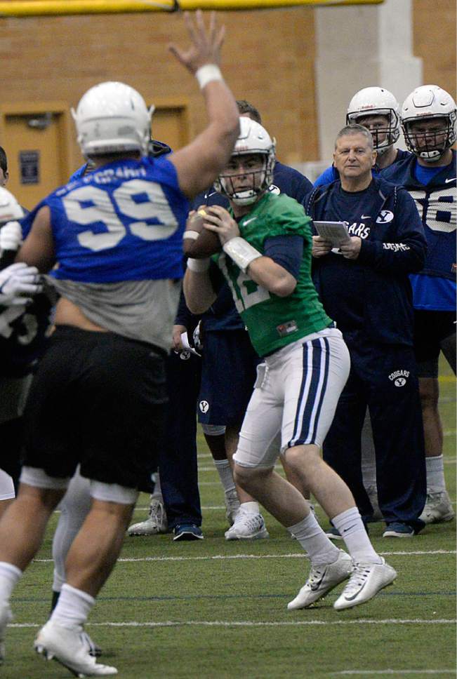 Al Hartmann  |  The Salt Lake Tribune
Starting quarterback Tanner Mangum takes a throw over defensive lineman Solomone Wolfgramm as BYU starts Spring training camp on Monday Feb. 27 at the Indoor Practice Facility.