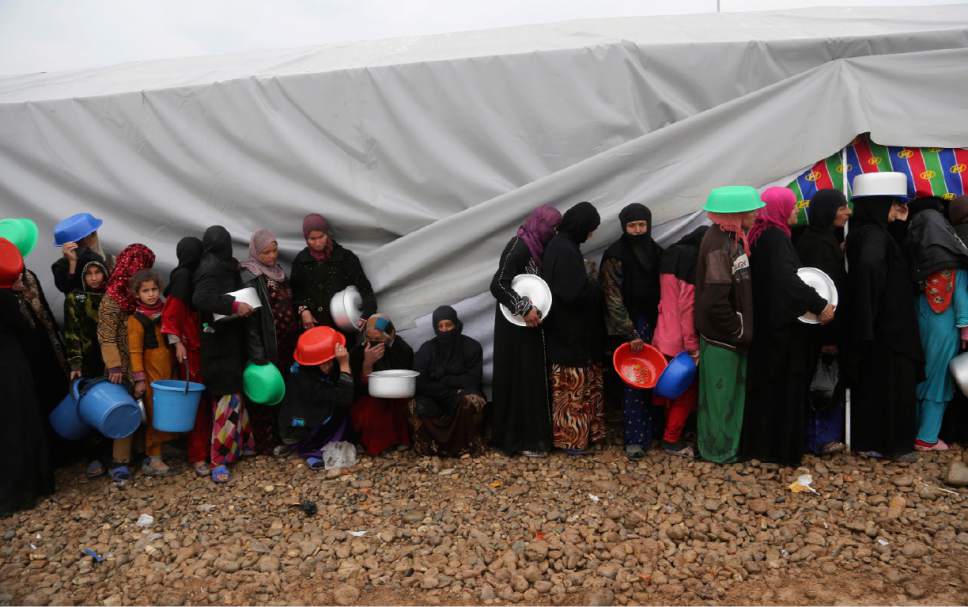 Displaced Iraqis, who fled fighting between Iraqi security forces and Islamic State militants, gather for food at a camp for internally displaced people, in Hamam al-Alil, some 10 kilometers south of Mosul, Iraq, Thursday, March 2, 2017. (AP Photo/ Khalid Mohammed)