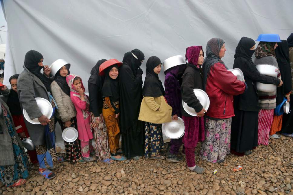 Displaced Iraqis, who fled fighting between Iraqi security forces and Islamic State militants, line up to receive  food, at a camp for internally displaced people, in Hamam al-Alil, some 10 kilometers south of Mosul, Iraq, Thursday, March 2, 2017. (AP Photo/ Khalid Mohammed)
