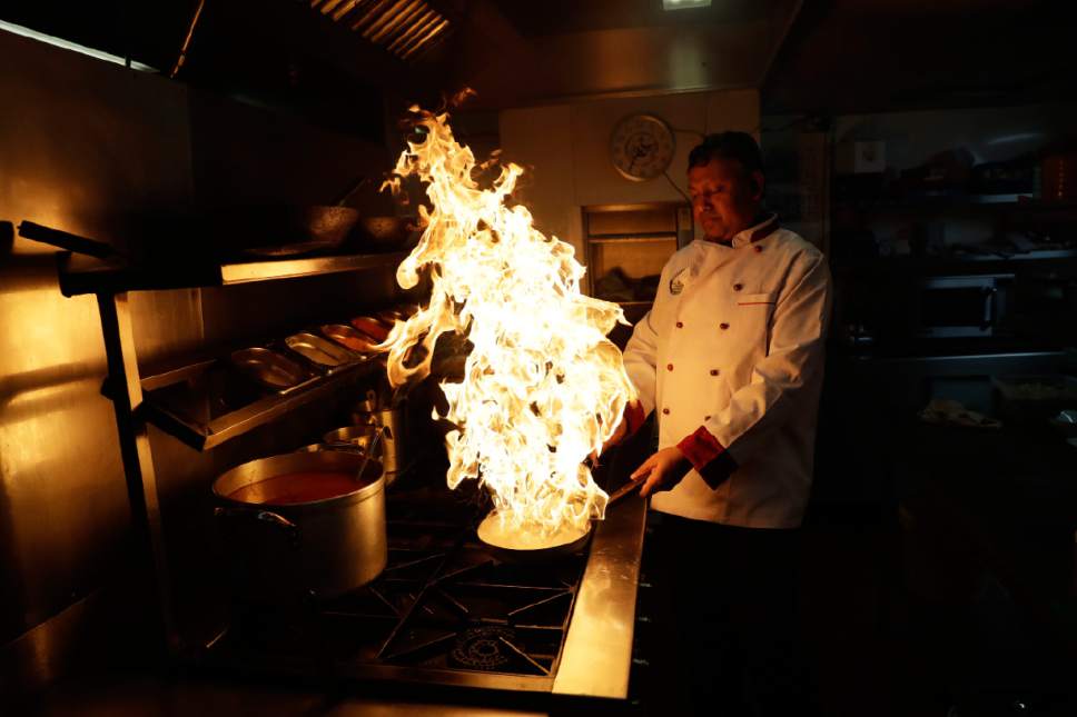 Chef Mohammed- Faizul Haque uses lemon juice to make flames as he demonstrates how to give a smokey flavour to dishes such as Kuchi Chilli Chicken at the  Taste of India curry restaurant in London, Thursday, March 9, 2017.  Curry shop owners in Britain fear that the onset of Brexit will add to their woes and force many of their shops to close. Many owners had backed the campaign to leave the European Union after assurances it would lead to more visas for South Asian cooks. (AP Photo/Matt Dunham)
