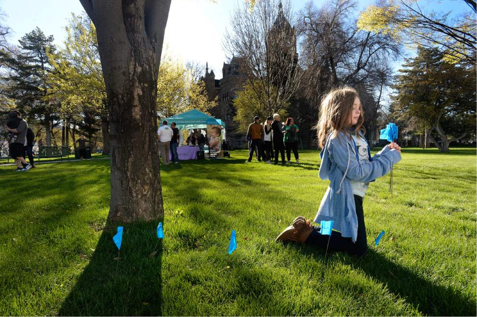 Scott Sommerdorf | The Salt Lake Tribune
A young girl helped the Carmen B Pingree Autism Center of Learning to place some of the 16,000 blue flags on the lawn at Washington Square Park, Saturday, April 1 2017. The flags represent the 1 in 58 children in Utah who will be diagnosed with autism.