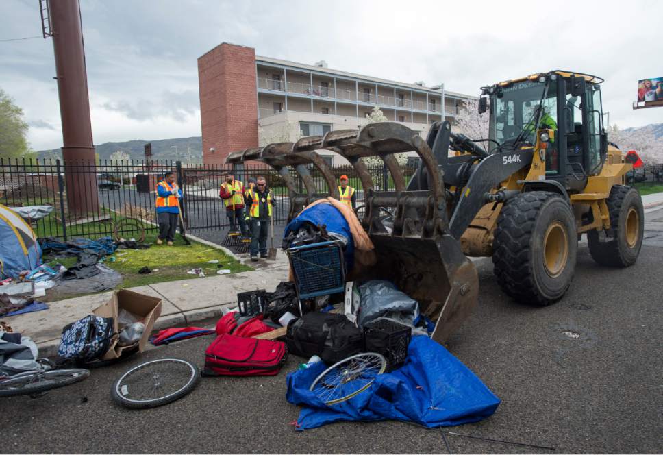 Rick Egan  |  The Salt Lake Tribune

Heavy equipment is used to move blankets, tents and bicycles on 600 South, as workers from the Salt Lake County Health Department and Salt Lake City Waste and Recycling Division clean up campsites along the street. Friday, March 31, 2017.