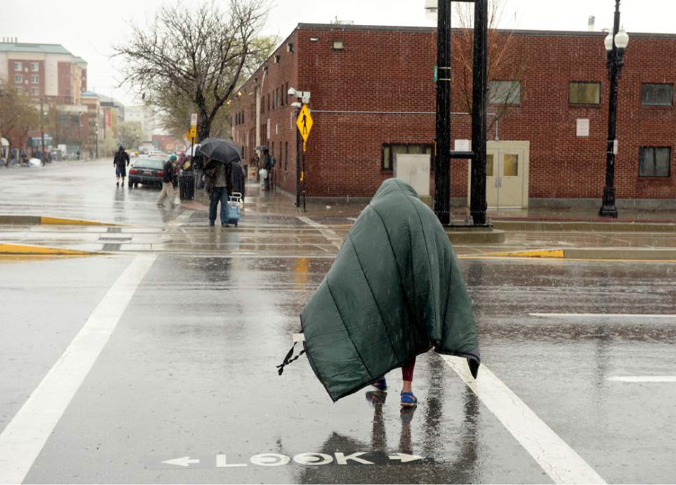Al Hartmann  |  The Salt Lake Tribune
A homeless man covers up with his sleeping bag from the pounding rain Monday March 27 to use pedestian crosswalk at 200 South to cross from the Gateway mall back to the homeless shelter at Rio Grande Street. Salt Lake City and the Utah Transit Authority plan to close the mid-block pedestrian crossing. Officials say the move is about public safety, but the project comes at the urging of the Gateway owners.