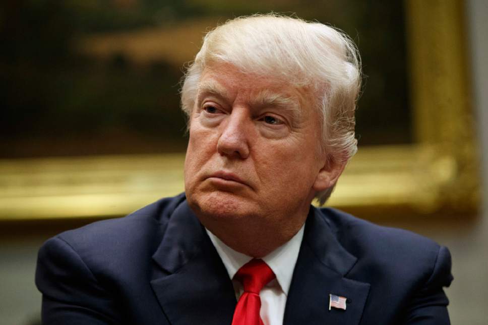 In this March 31, 2017, photo, President Donald Trump listens during a meeting with the National Association of Manufacturers in the Roosevelt Room of the White House in Washington. Slim majorities of Americans favor independent investigations into Trump's relationship with the Russian government and possible attempts by Russia to influence last year's election according to a new poll by The Associated Press-NORC Center for Public Affairs Research. (AP Photo/Evan Vucci)