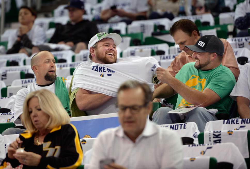 Scott Sommerdorf | The Salt Lake Tribune
A Jazz fan gets a little help putting on one of the "Take Note" t-shirts that were placed on each seat prior to Game 3 of the Western Conference playoff series,Friday, April 21, 2017.