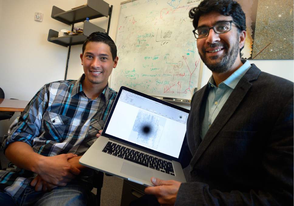 Scott Sommerdorf | The Salt Lake Tribune
University of Utah researchers Christopher Ahn, left, and Anil Seth pose for a photo with an image associated with their discovery of two new black holes, Wednesday, April 19, 2017. The pair have published a paper about their discovery which bolsters their theory that black holes are located at the center of most galaxies, including the special class of small galaxy they have spent the last several years studying.