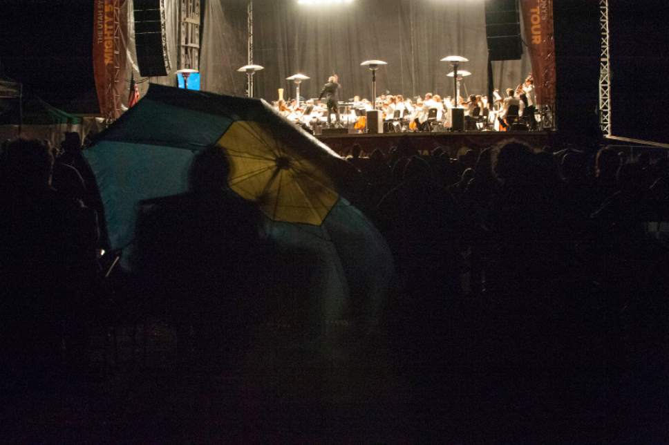 Ann Torrence  |  For The Salt Lake Tribune 
Umbrellas protect spectators as Utah Symphony plays through a rain shower during its Mighty 5 Tour on Tuesday, Aug. 12, 2014 in Teasdale, Utah.