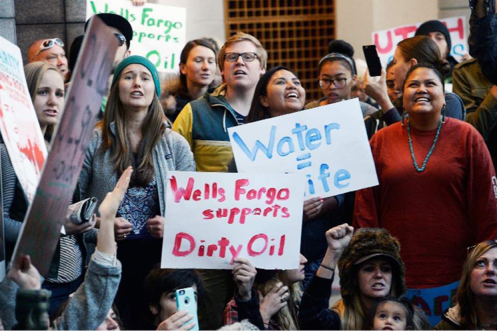 FILE - In this Oct. 31, 2016, file photo, protesters hold a rally in the lobby of the Wells Fargo Center building in Salt Lake City in support of the Standing Rock Sioux against the Dakota Access pipeline. Opposition to the four-state Dakota Access oil pipeline has boosted efforts to persuade banks to stop supporting projects that might harm the environment or tread on indigenous rights. (Al Hartmann/The Salt Lake Tribune via AP, File)