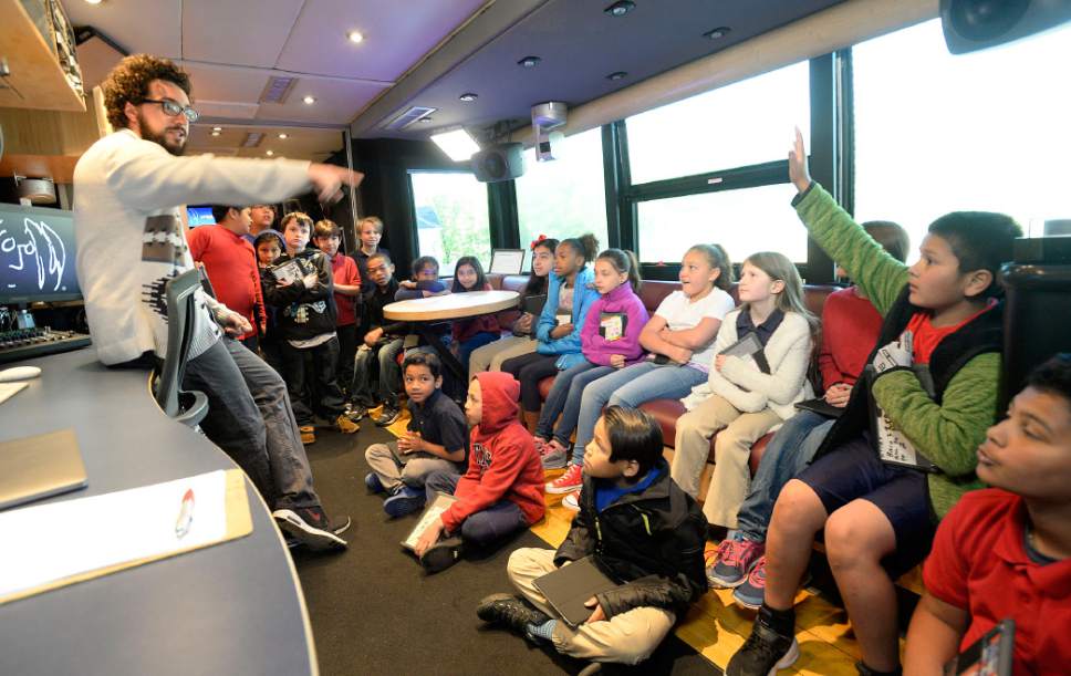Al Hartmann  |  The Salt Lake Tribune
Jackson Elementary fourth graders tour the John Lennon Educational Tour Bus Wednesday May 17.  Gabe Smith, on board engineer, explains the state-of-the-art mobile audio, video and live production facility on board.  
In its 20th year, with the very newest technology and gear, the bus provides young people with career development tours of the studios and offers free digital media production workshops.
In the workshops, assisted by three on-board engineers, students learn how to write, record, and produce original songs, music videos, documentaries, and live multi-camera video productions, using the most up-to-date  IT Solutions .
