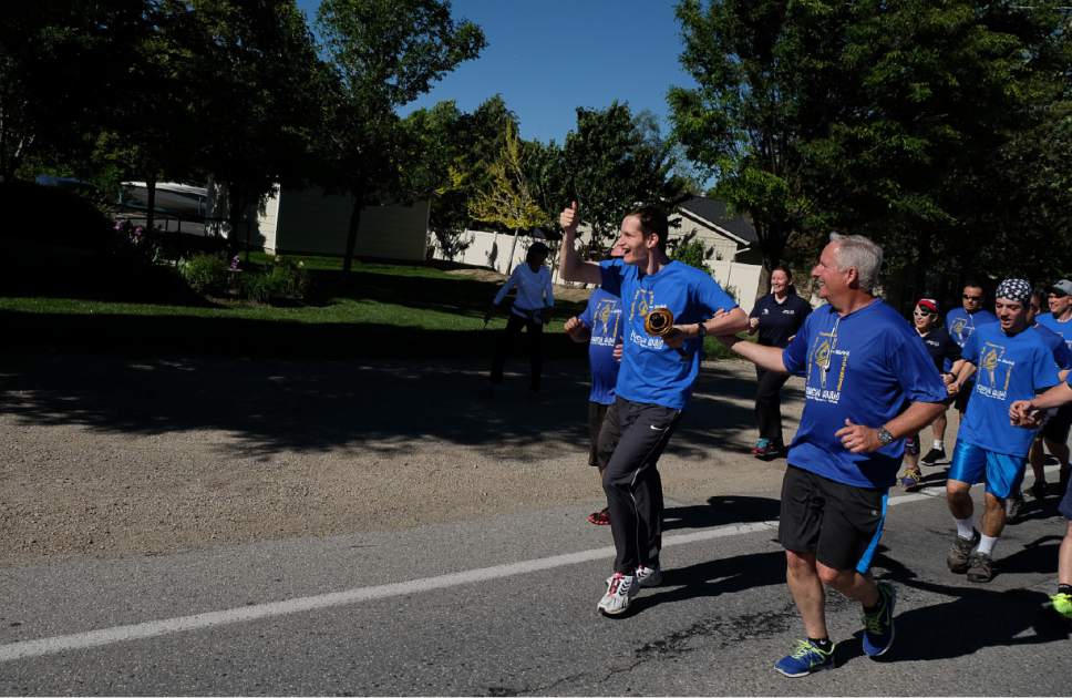 Francisco Kjolseth | The Salt Lake Tribune
Special Olympics athlete Truman Whitmer holds the torch high as members of the Draper Police Department participate in the annual Law Enforcement Torch Run for Special Olympics Utah by helping carry the "Flame of Hope" from 11400 South State Street to Draper City Hall on Wed. May 24, 2017.