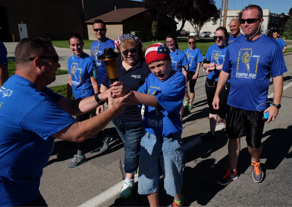 Francisco Kjolseth | The Salt Lake Tribune
Davis Pauley is handed the Special Olympics torch by officer Mike Elkins as members of the Draper Police Department participate in the annual Law Enforcement Torch Run for Special Olympics Utah by helping carry the "Flame of Hope" from 11400 South State Street to Draper City Hall on Wed. May 24, 2017.