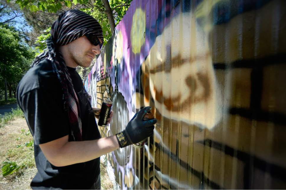 Scott Sommerdorf | The Salt Lake Tribune
Justin Johnson finishes his panel as he and Glendale Middle School students installed a mural on a length of fence next to the Jordan Parkway Trail, Friday, June 2, 2017.