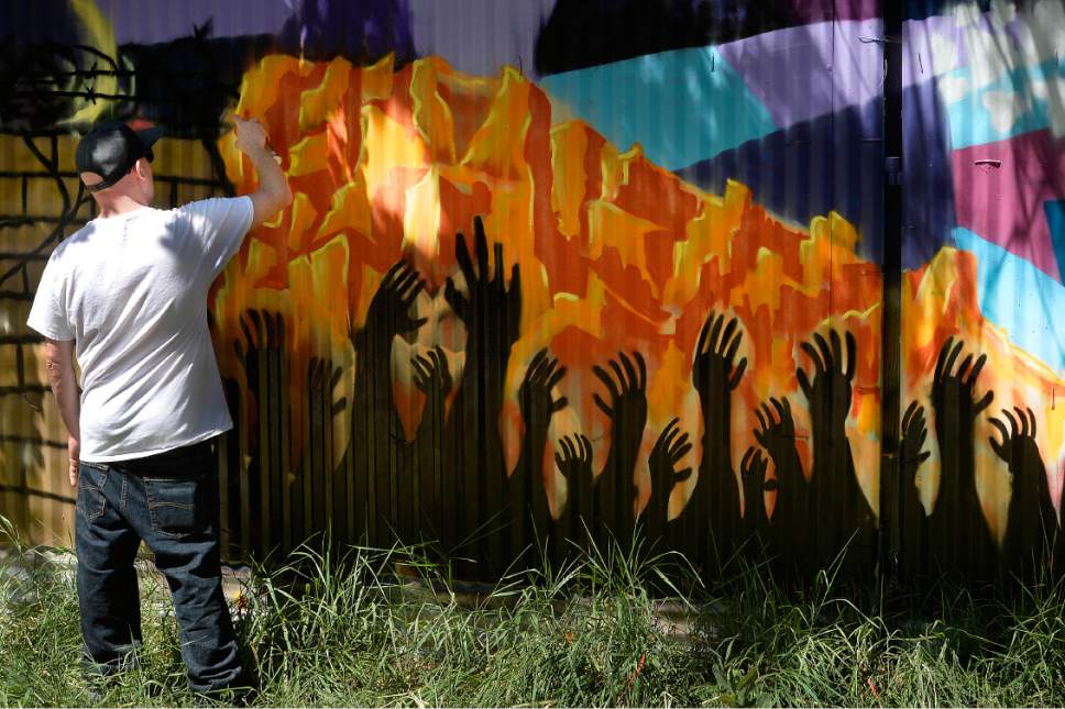 Scott Sommerdorf | The Salt Lake Tribune
Ryan Worwood put the finishing touches on his panel as local artists with Justified Ink worked together with Glendale Middle School students to install a mural on a length of fence next to the Jordan Parkway Trail, Friday, June 2, 2017.