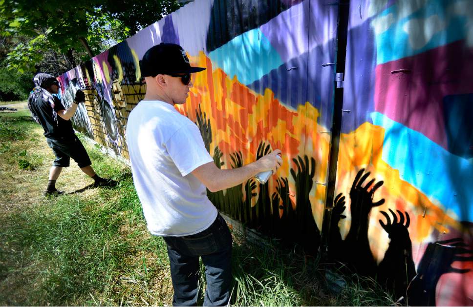 Scott Sommerdorf | The Salt Lake Tribune
Justin Johnson, left and Ryan Worwood put the finishing touches on their panels as local artists with Justified Ink worked together with Glendale Middle School students to install a mural on a length of fence next to the Jordan Parkway Trail, Friday, June 2, 2017.