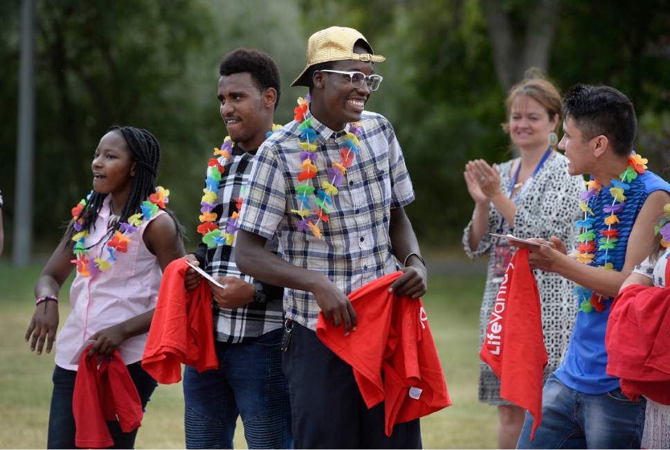 Scott Sommerdorf | The Salt Lake Tribune
Jolly Karungi, left, Eric Mugisha, center, and Reza Hussaini, right, all refugees who came to Utah, react as they take in a round of applause in their honor at a party for 14 refugee foster care teens who earned their high school diplomas this year. The celebration was put on by Catholic Community Services of Utah, and held at Jordan Park, Friday, June 9, 2017.