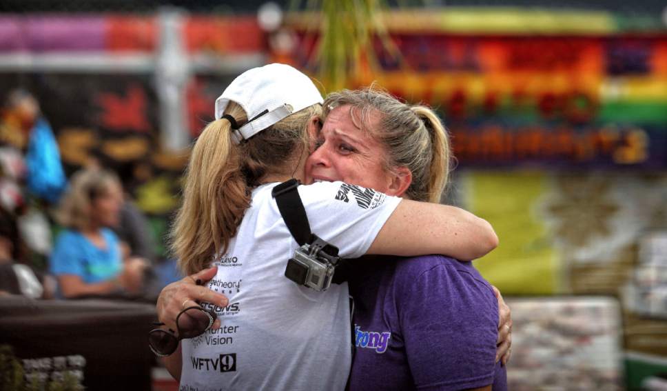 Runners Randa Black, left, and Elizabeth Anne-Noles cry after stopping in front of the Pulse nightclub during the CommUNITYRainbowRun 4.9K road race, Saturday, June 10, 2017, in Orlando, Fla. The race is one of many events across central Florida commemorating the one-year anniversary of the June 12, 2016 massacre at the club that left 49 people dead. (Joe Burbank/Orlando Sentinel via AP)