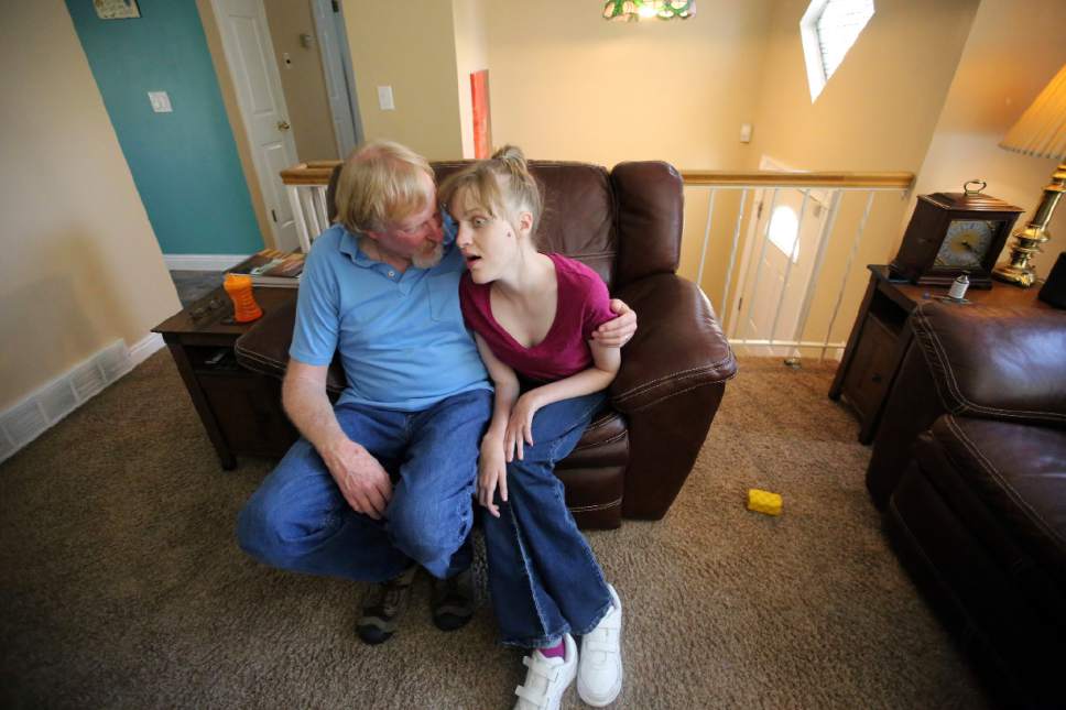 This June 6, 2017, photo, Utah resident Doug Rice, hugs his daughter Ashley, 24, at their home in West Jordan, Utah. Utah lawmakers balked again this year at joining more than half of all U.S. states and passing a broad medical marijuana law. Rice says Utah's approach means his daughter, who has a genetic condition, is missing out on the one drug that eliminates her frequent seizures. (AP Photo/Rick Bowmer)